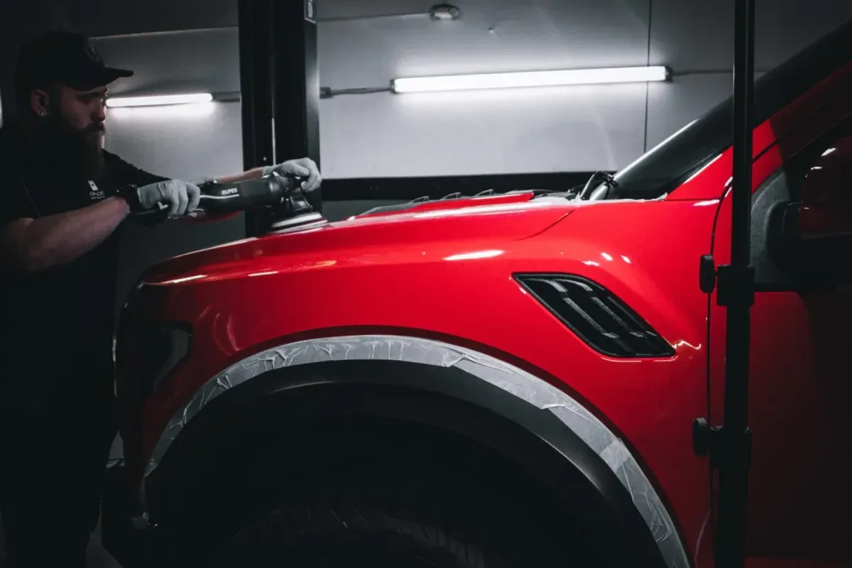 Technician machine-polishing red vehicle paint